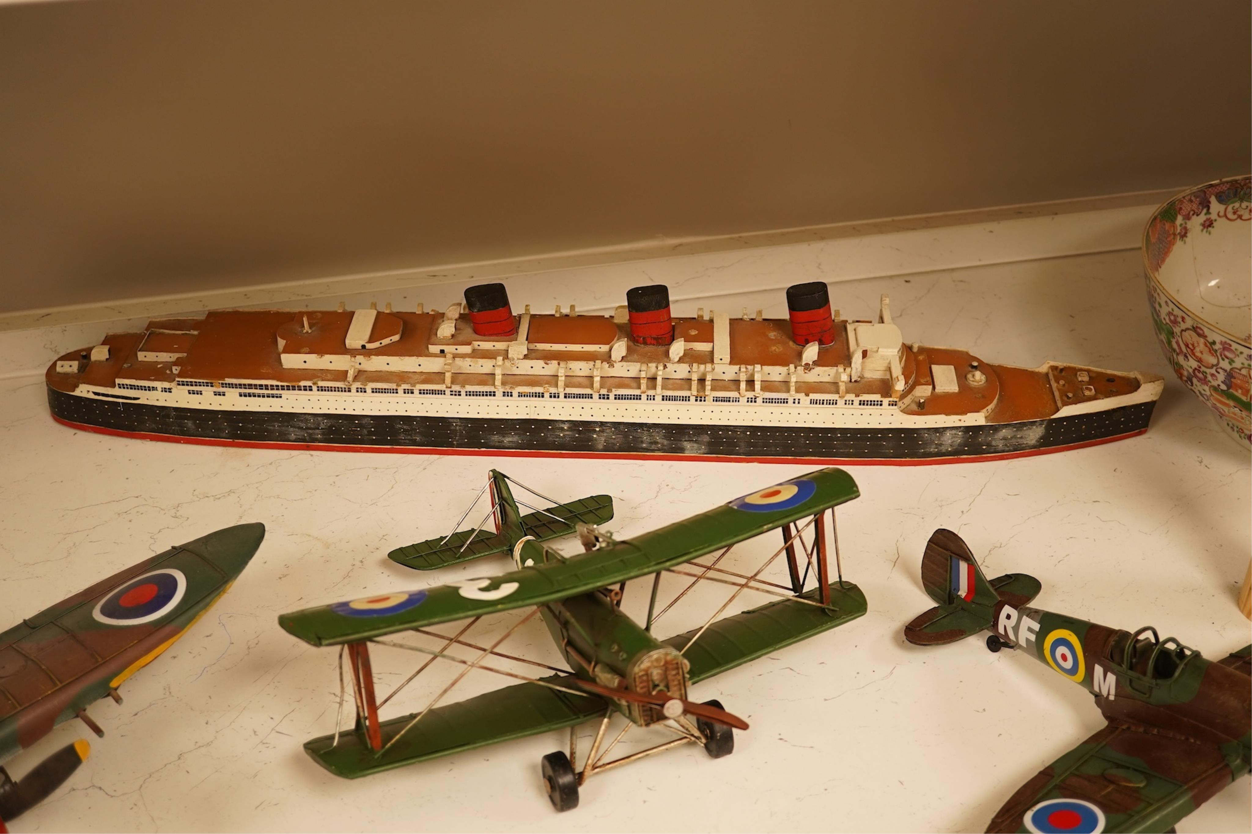 Five decorative metal models of military aircraft, including two Supermarine Spitfires, two First World War, British bi-planes, a German Albatros D.III bi-plane, and a wooden model of RMS Queen Mary, hull 77cm long